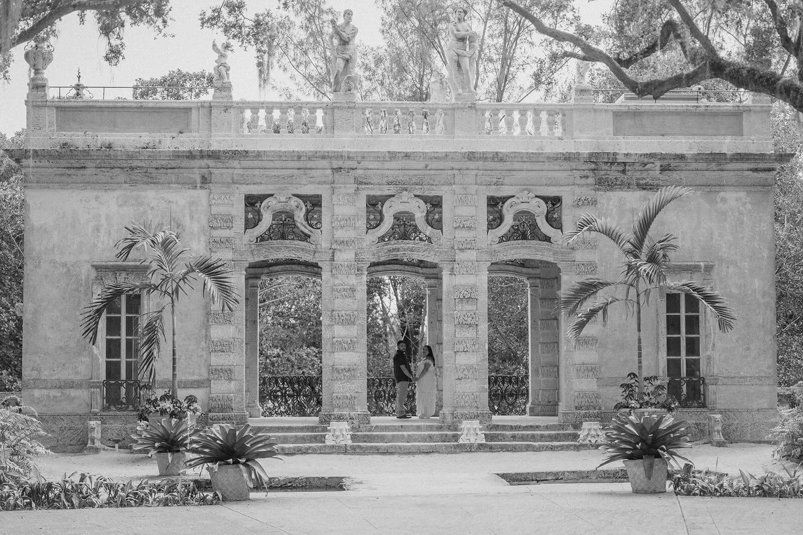 a couple standing in a structure during their miami engagement photo shoot