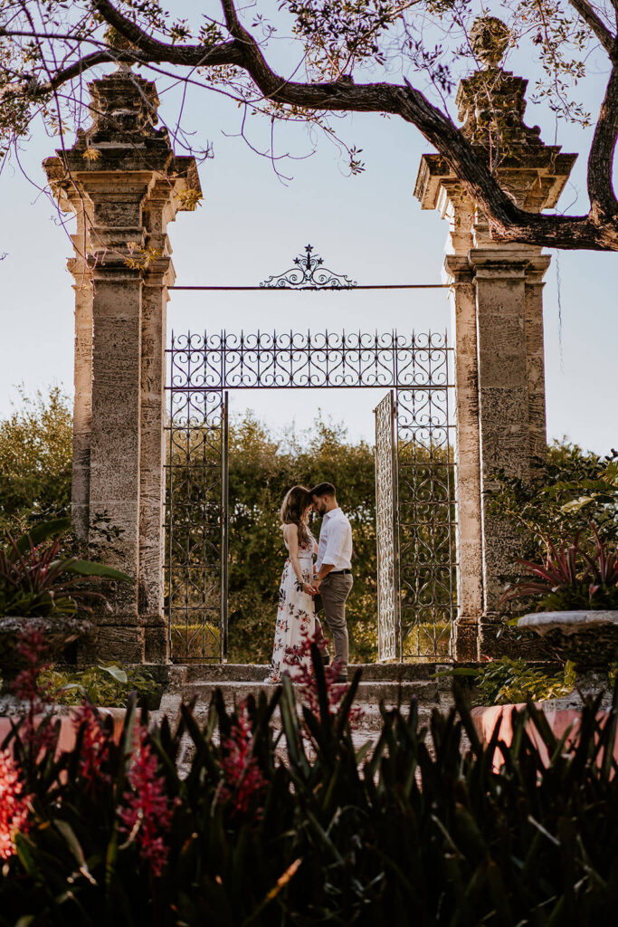 a couple with foreheads together under a gate at their engagement shoot in Miami