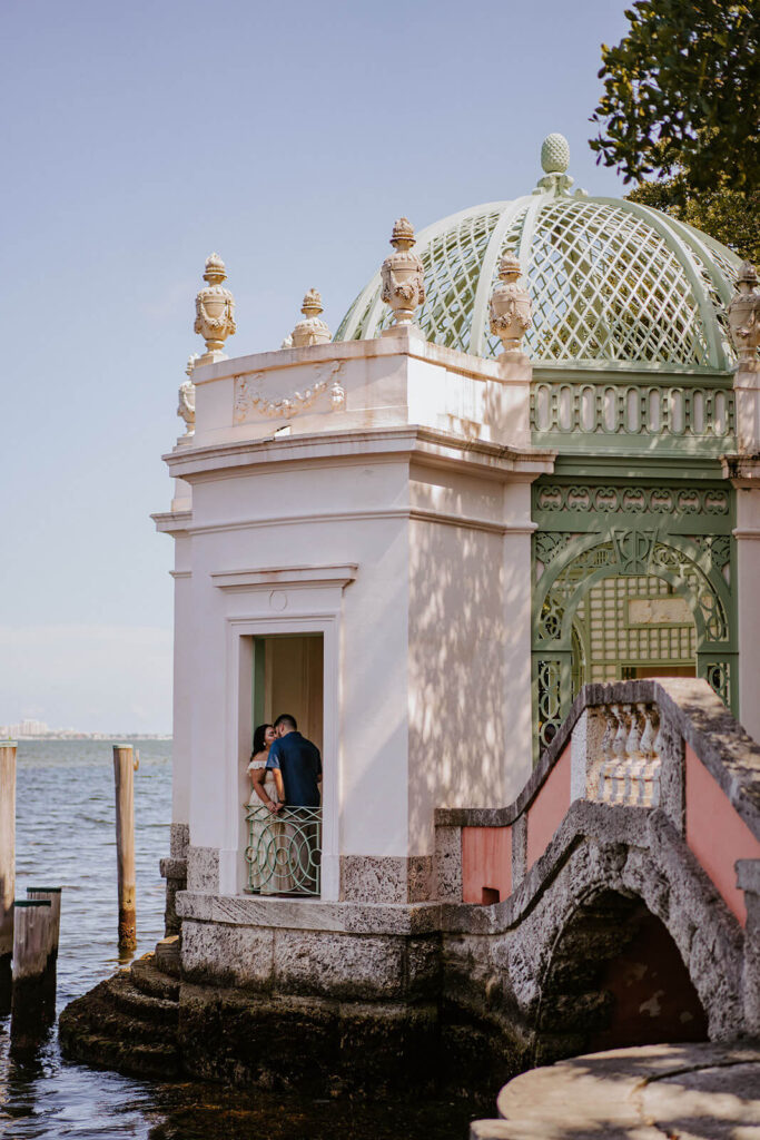 a couple kissing while hanging out of a gazebo on their engagement shoot