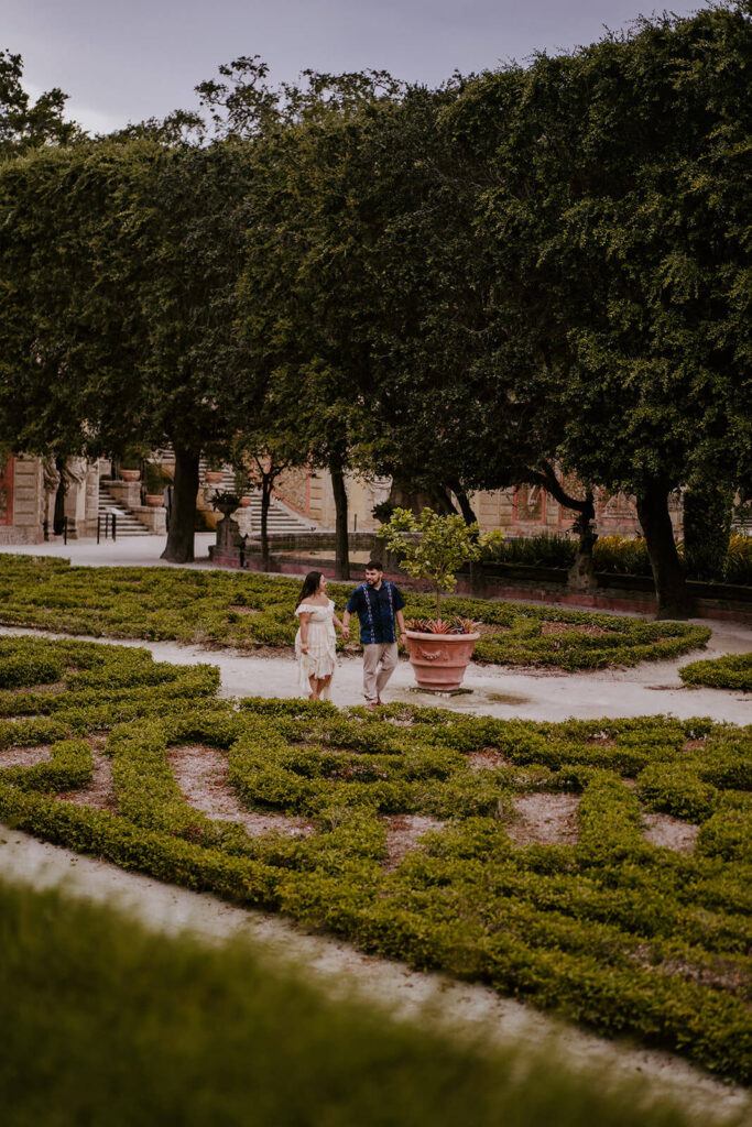 a couple walking through the gardens of Vizcaya Museum on their engagement shoot