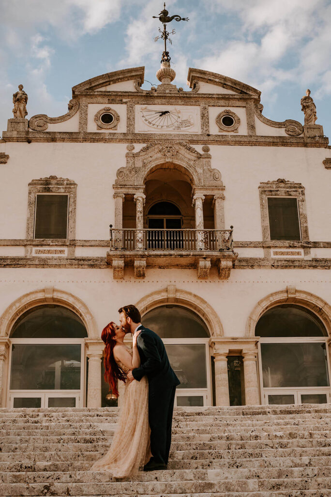 a bride and groom kiss in front of Vizcaya Museum and Gardens