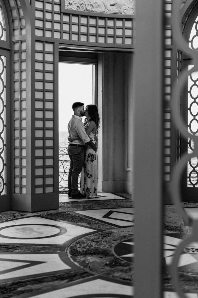 a couple kissing inside of the gazebo in the gardens