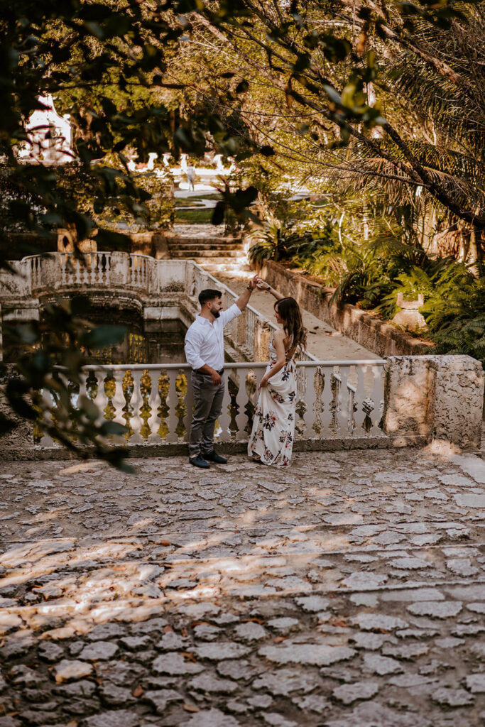 a man twirls his fiance in front of a beautiful garden in Miami