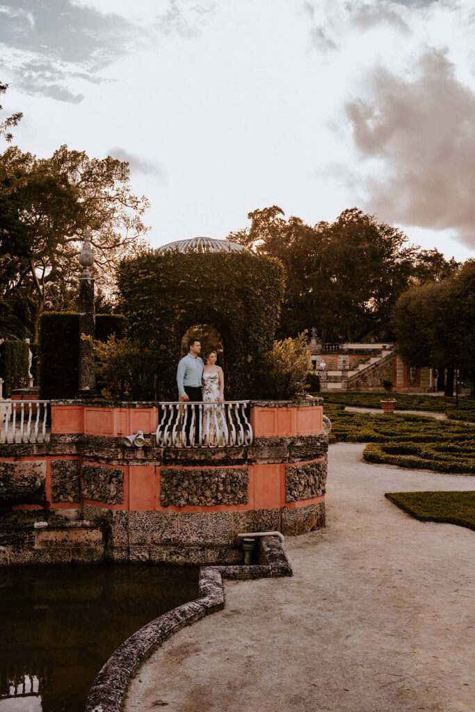 a couple stands in the middle of the arch covered in greenery at Vizcaya