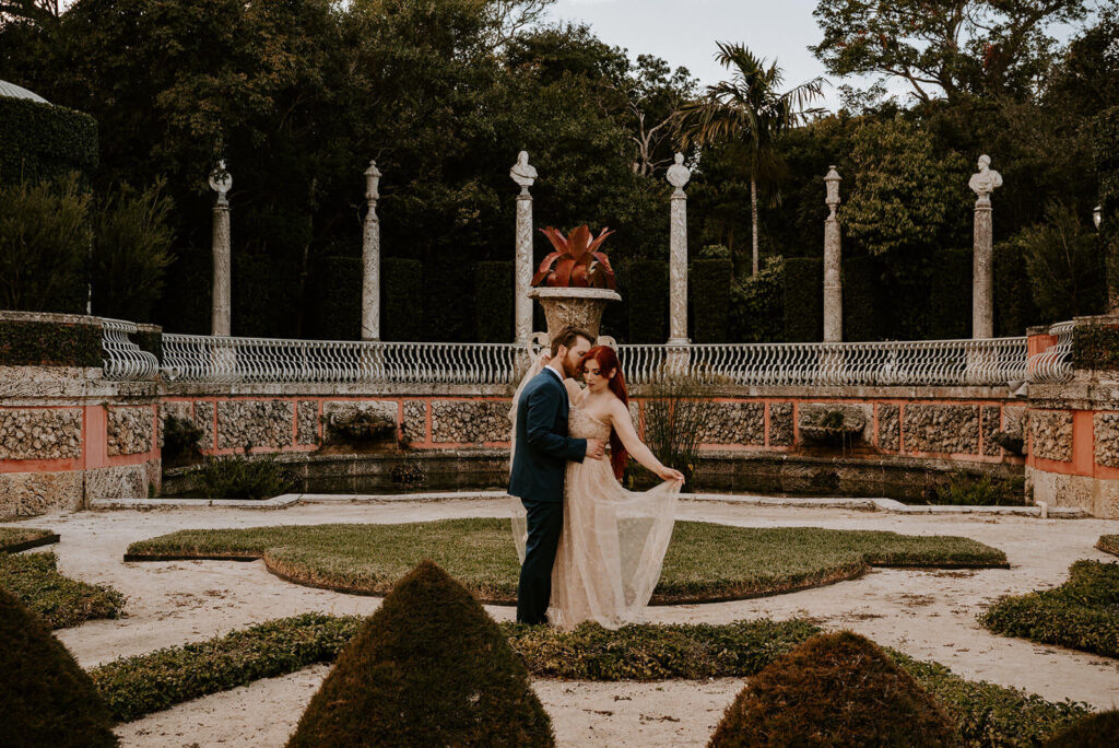a bride and groom pose in the middle of the courtyard surrounded by columns