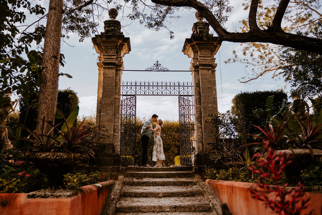 a bride and an groom kiss under a gate at Vizcaya