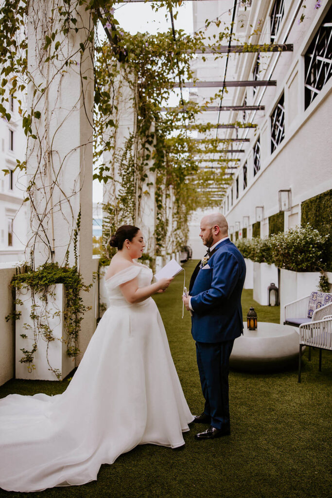 a bride and groom read their vows to each other surrounded by greenery at their wedding venue in Miami