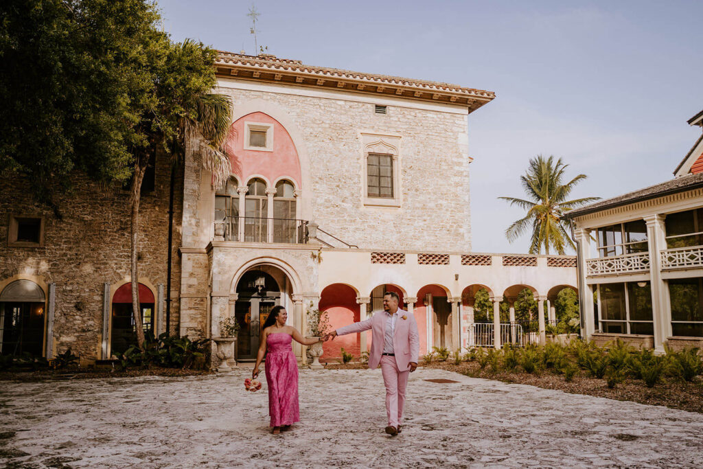 a bride and groom hold hands while walking through their luxury miami wedding venue
