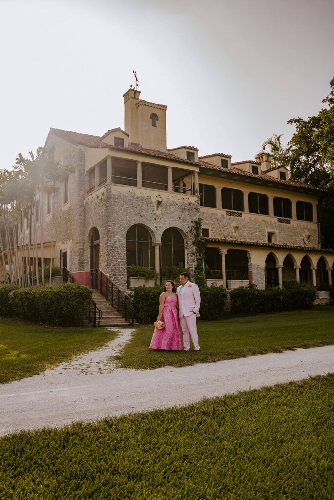 a bride and groom holding hands and posing in front of the Deering Estate