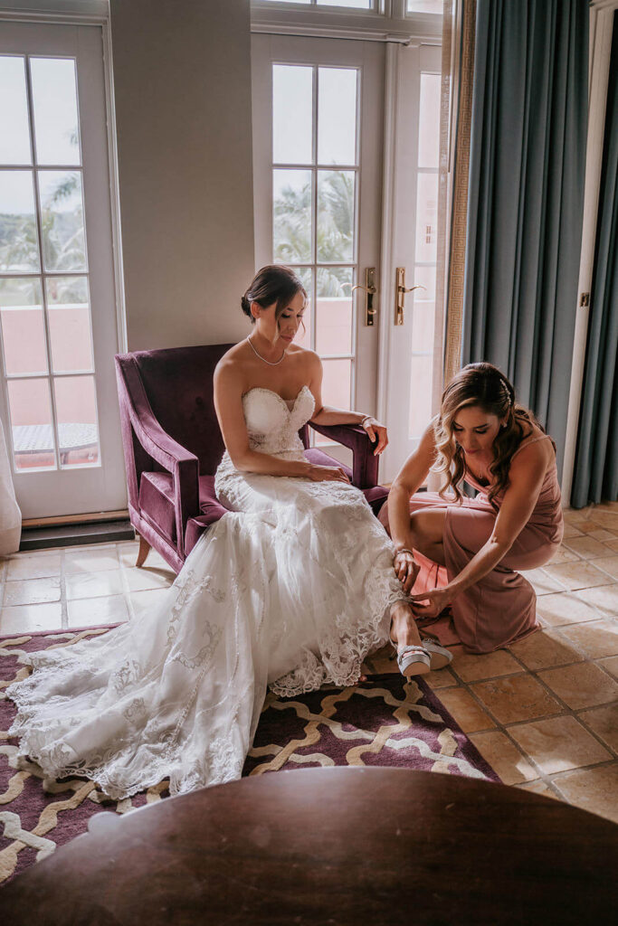 a sister helps her sister put on her wedding shoes at the Biltmore Hotel in Coral Gables