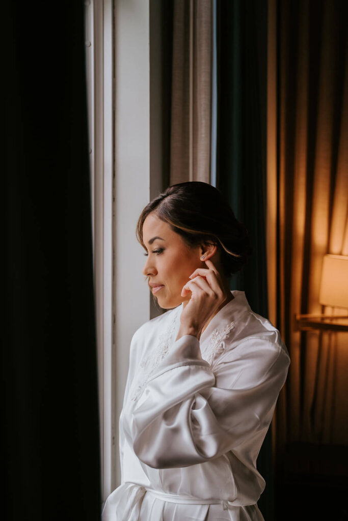 a bride puts on her earring while getting ready at the Biltmore Hotel in Miami
