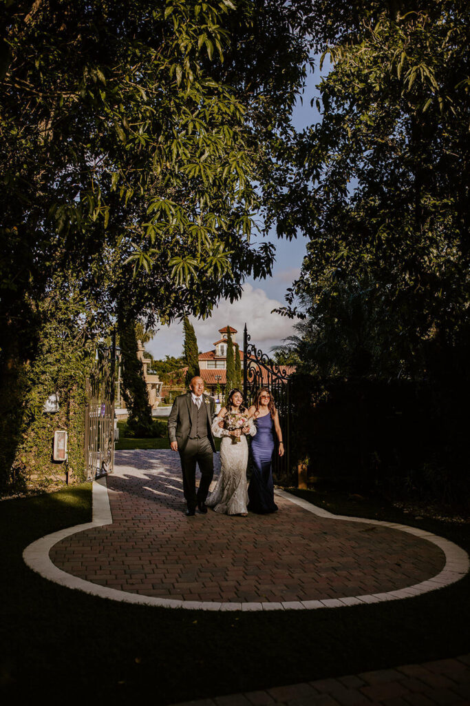 a bride walks into the ceremony location of her luxury miami wedding venue on her wedding with her parents