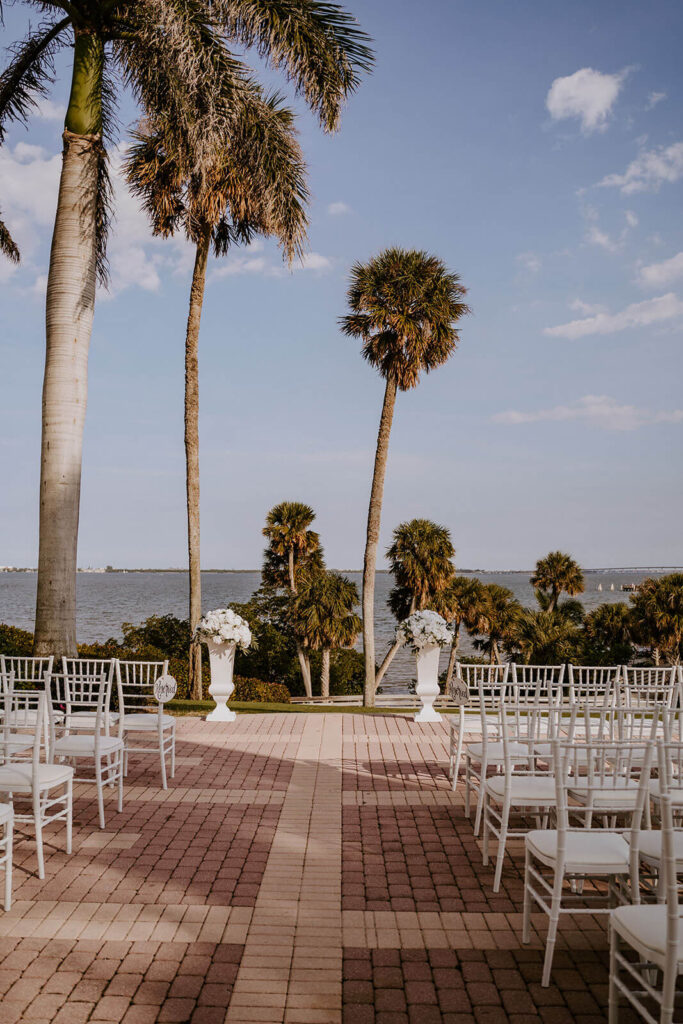 a ceremony location overlooking the ocean with white chairs and palm trees in florida