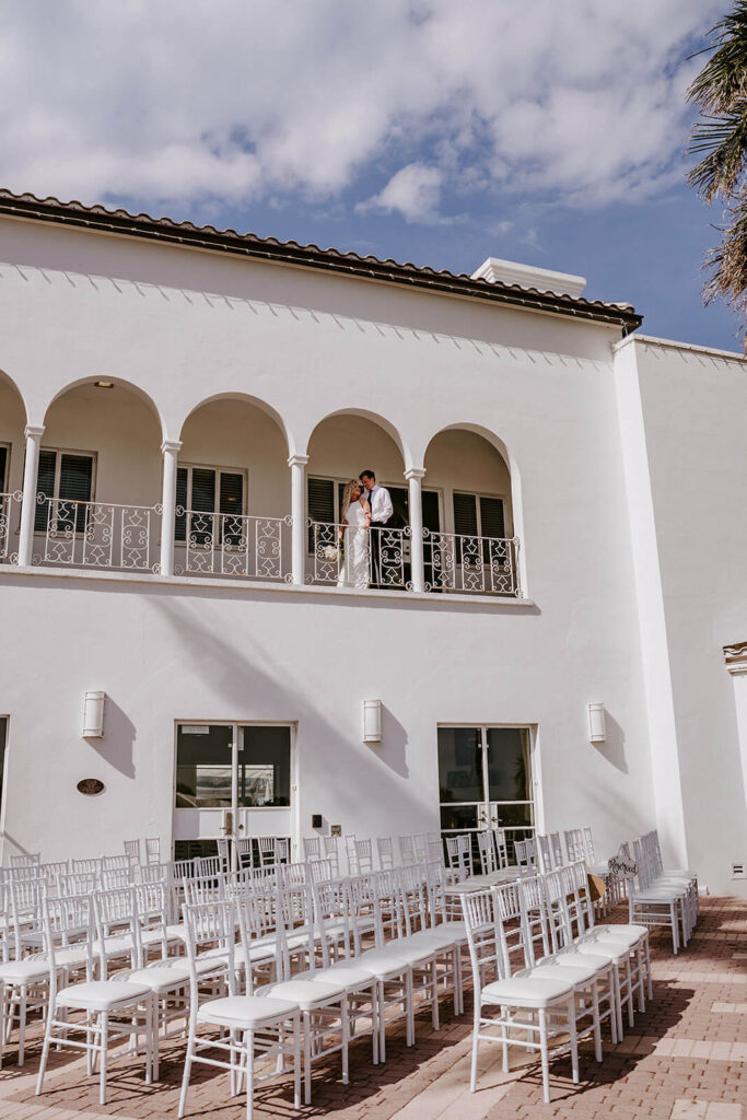 a couple poses on a balcony overlooking their ceremony space at their wedding at the Tuckahoe Mansion 