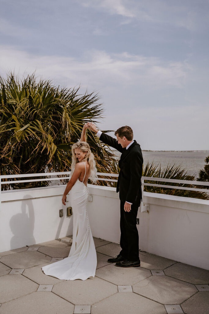 a groom turning his bride on a balcony overlooking the ocean in miami florida
