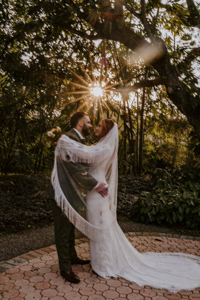 a couple hugging with their veil at golden hour at their 70's inspired wedding day
