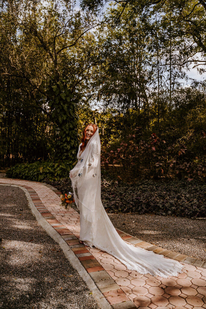 a bride laughs as she looks back and poses with her veil at the Gardens of Weber Manor