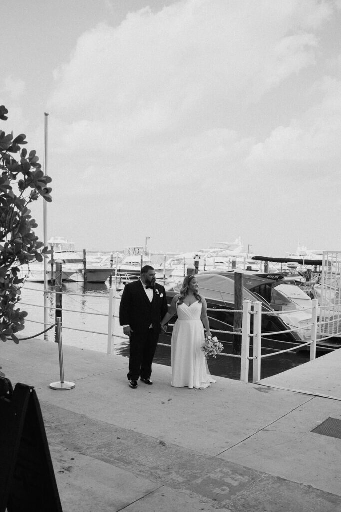 a bride and a groom posing for their couples portraits in front of boats at their wedding venue in miami