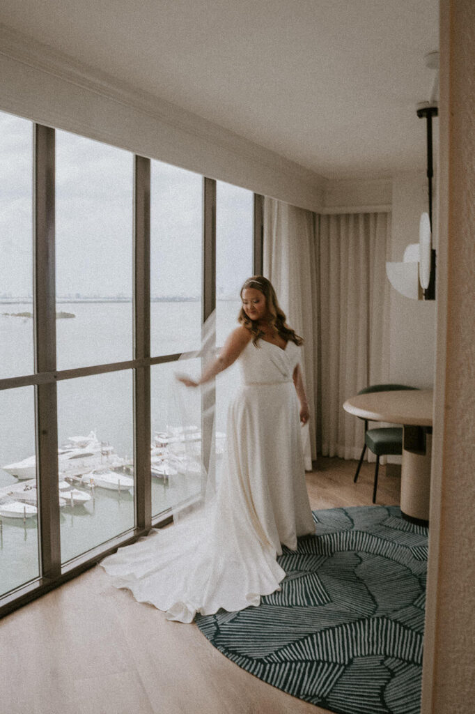 a bride plays with her veil as she gets ready over her wedding day overlooking the ocean in south florida