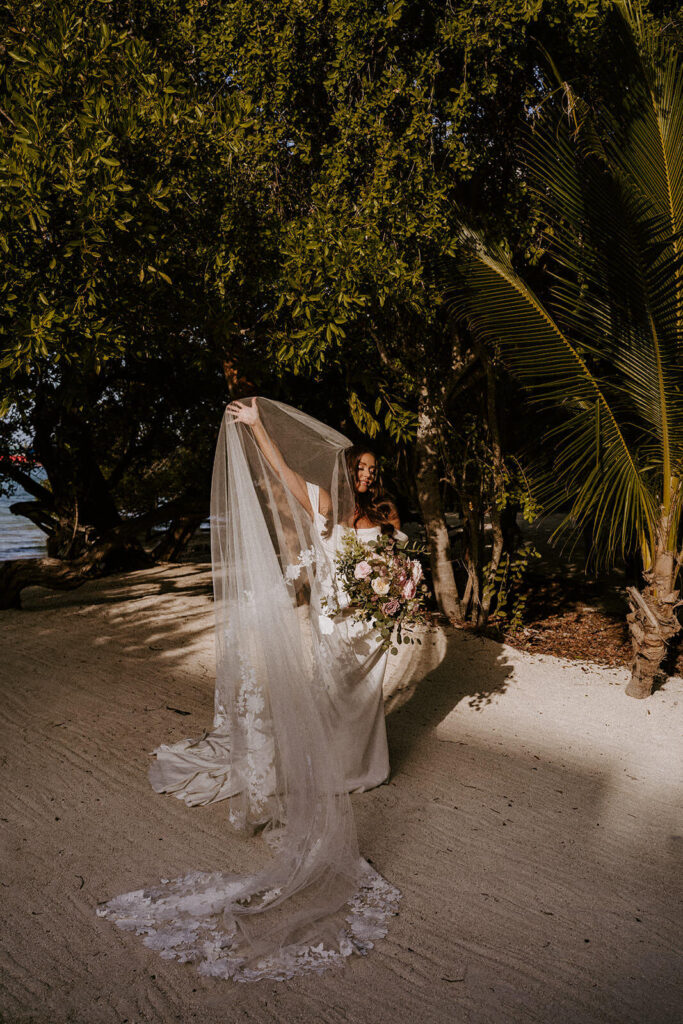 a bride plays with her veil in the golden sun at her wedding