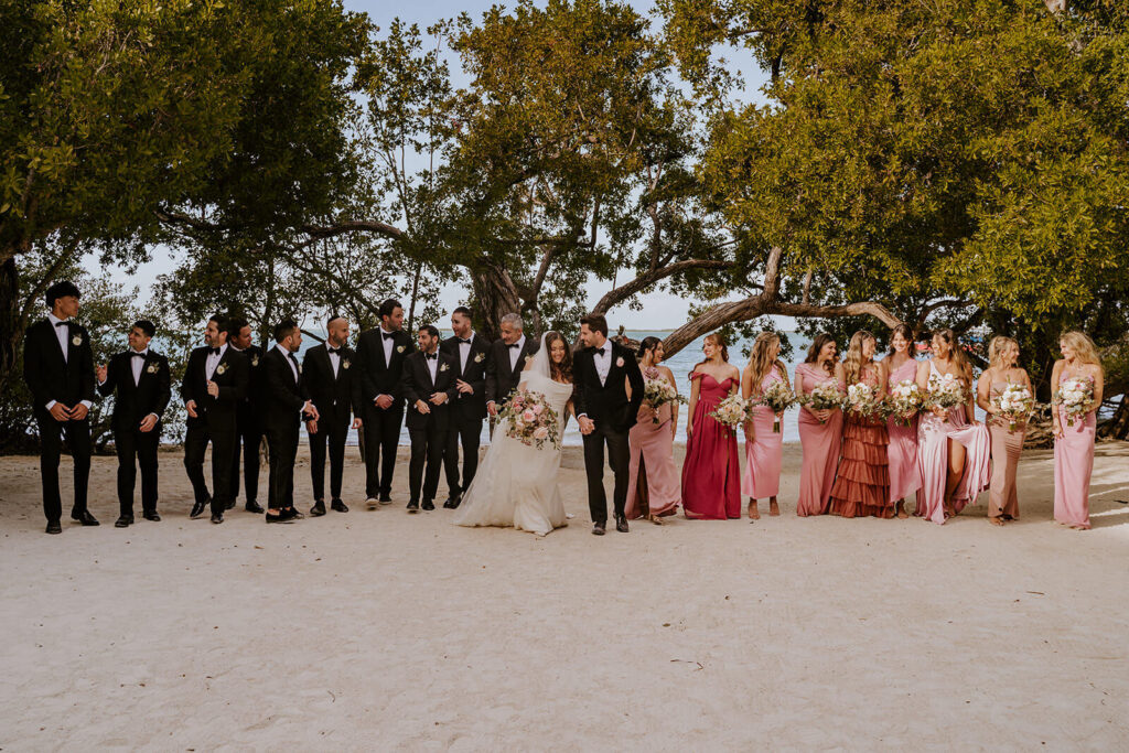 a bridal party all walking together with the miami palm trees behind them on a wedding day