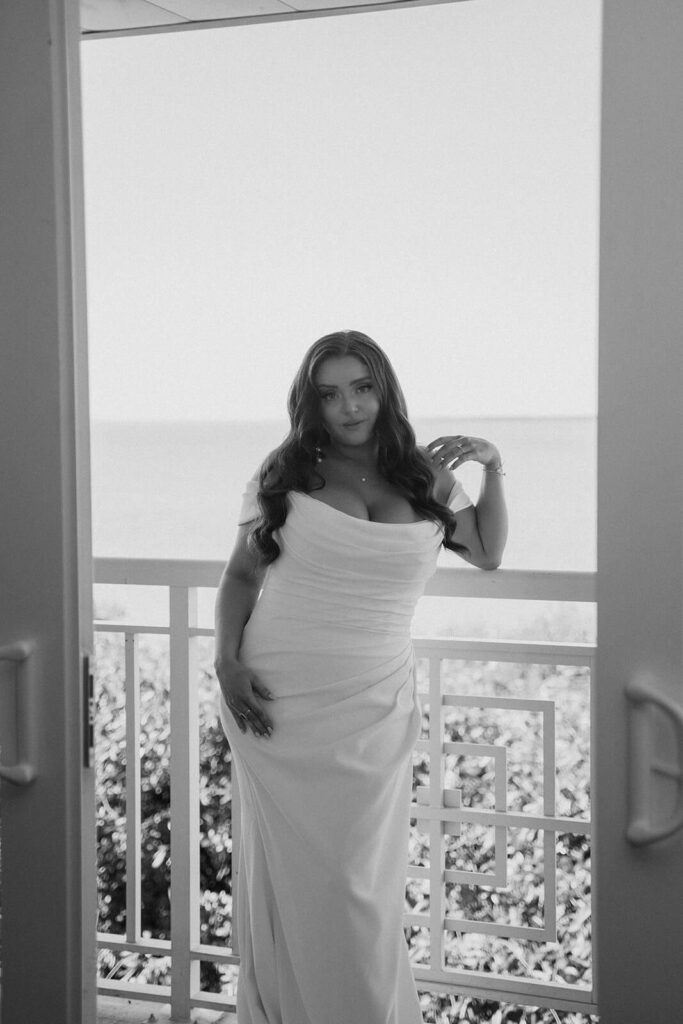 a bride posing with her wedding dress on a balcony over looking the water in miami 