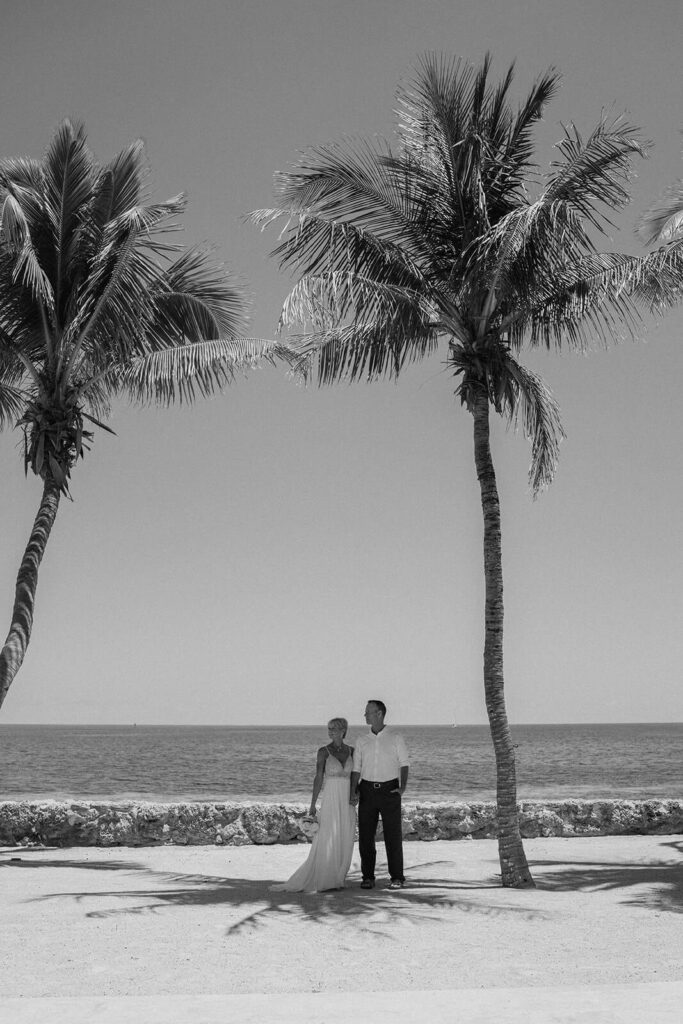a couple posing on their wedding day under the shadow of the palm trees at their wedding venue