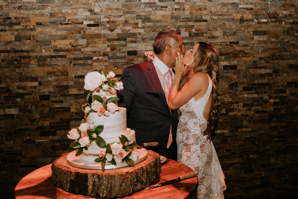 a bride and groom kiss after they cut their cake