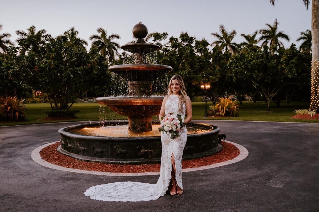a bride poses in front of the main fountain at a homestead wedding venue