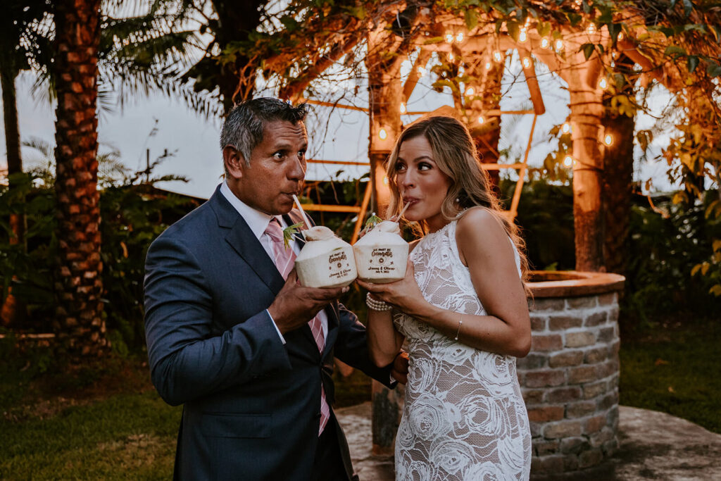 a bride and groom pose with their custom coconut drinks made for them at longans place 