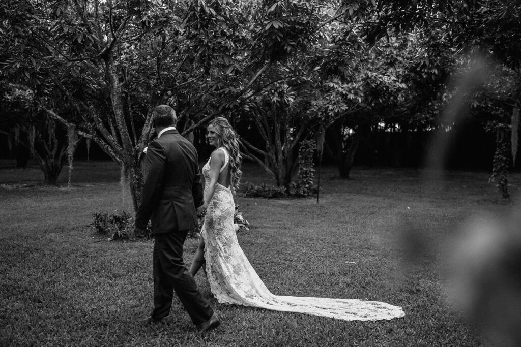 a bride and groom walk through the groves at their wedding venye