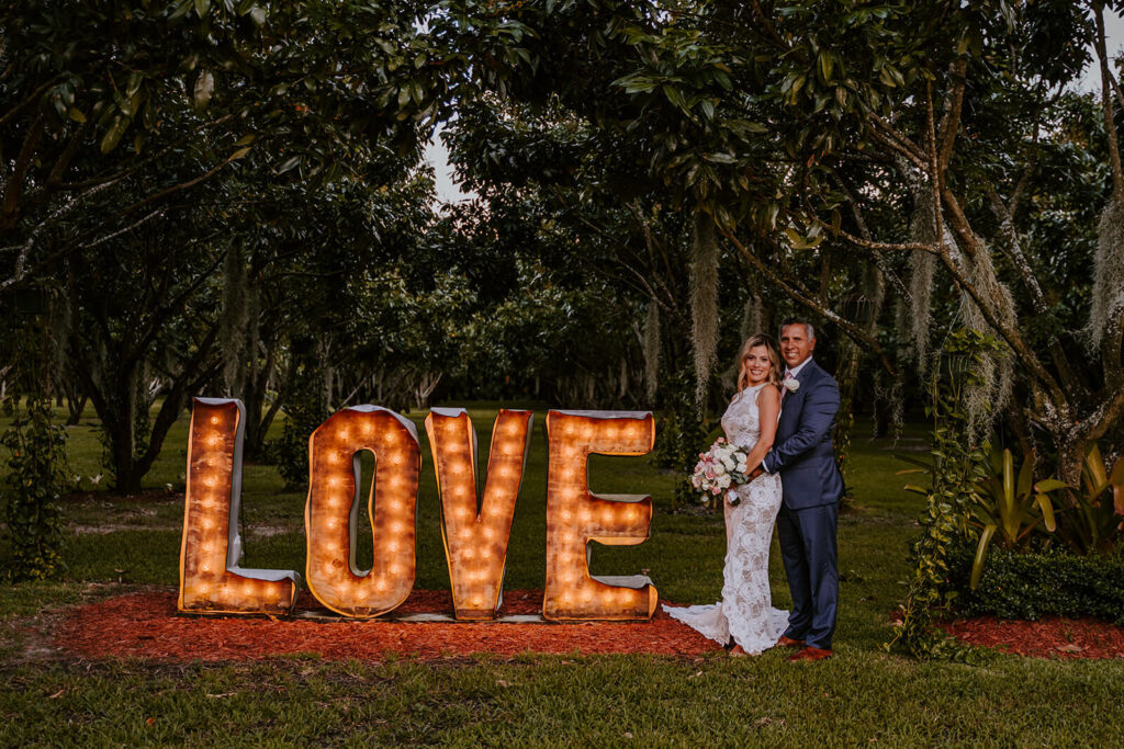 a couple poses with a big LOVE sign on their wedding day