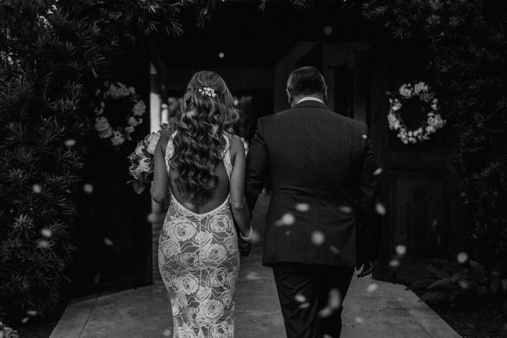 a couple walks hand in hand as they leave their ceremony on their wedding day