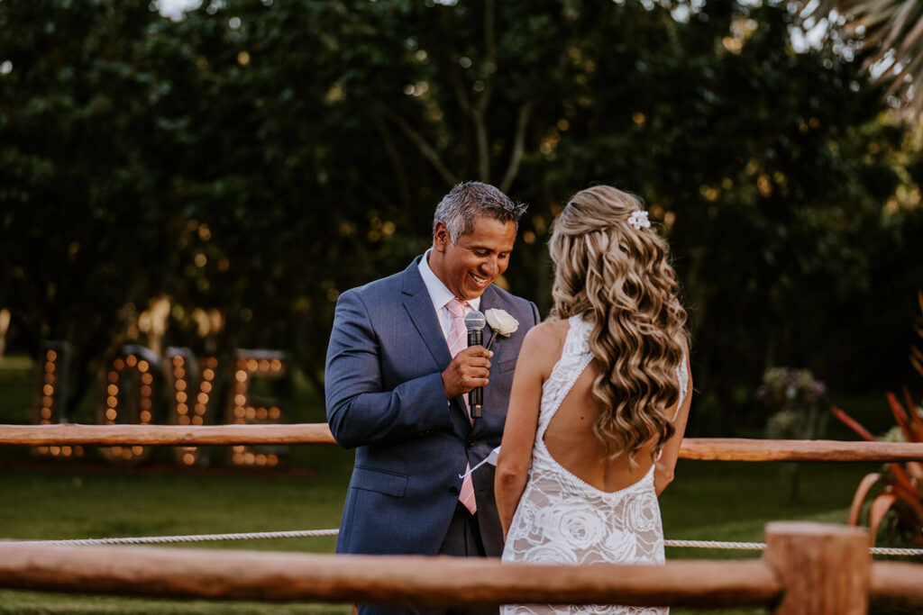 a grooms says his vows to his bride while smiling on their wedding day
