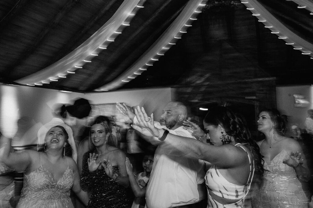 a black and white photo of guests dancing at a wedding reception