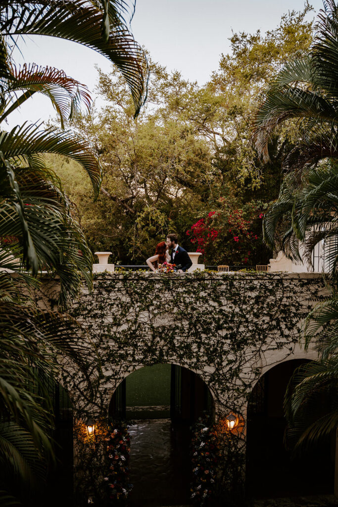 a couple kisses on their wedding day on a balcony at Villa Woodbine