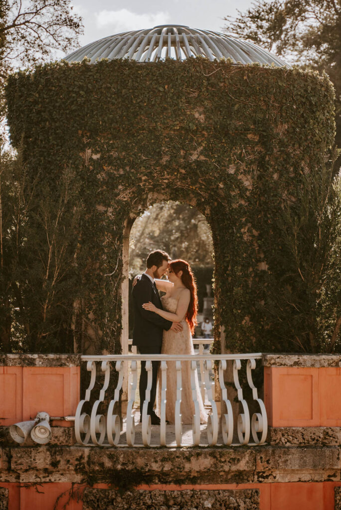 a couple hugs in an archway in the gardens of Vizcaya