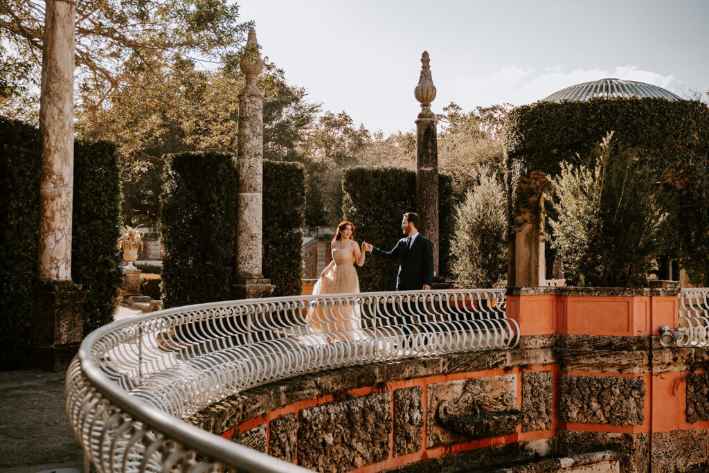 a couple walks through the gardens at Vizcaya in Coconut grove in their wedding outfits