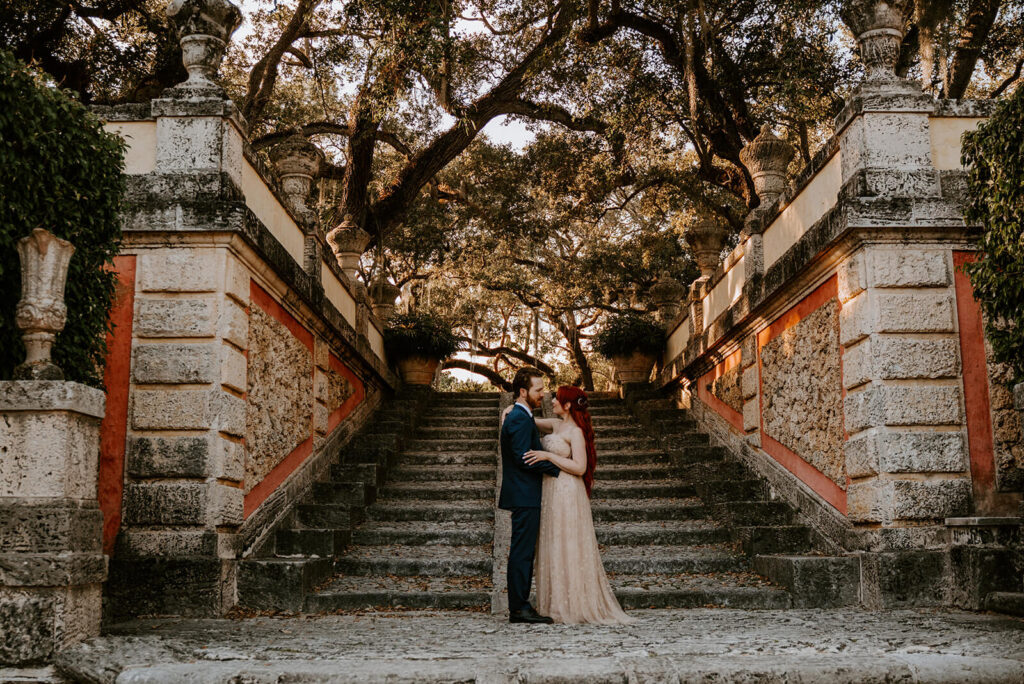 a couple poses in front of the steps at Vizcaya in Miami at golden hour