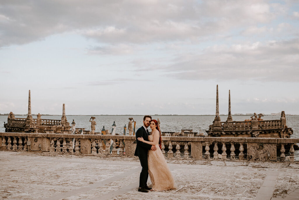 a couple poses in front of the ocean water at their coconut grove wedding venue