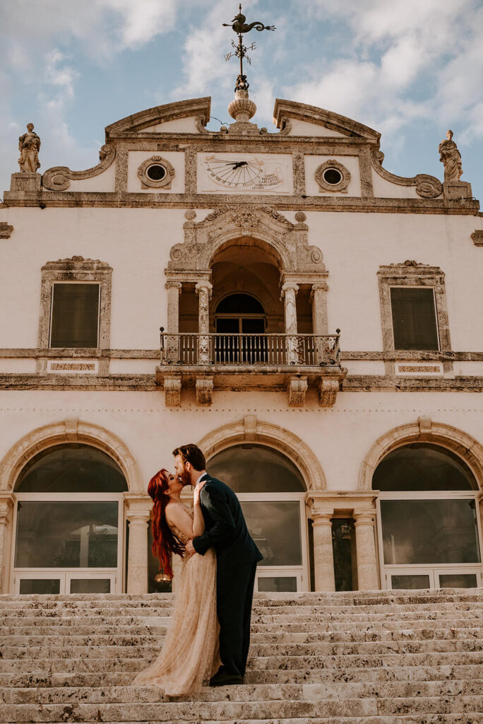 a couple kisses and dips at their miami wedding venue on their wedding day