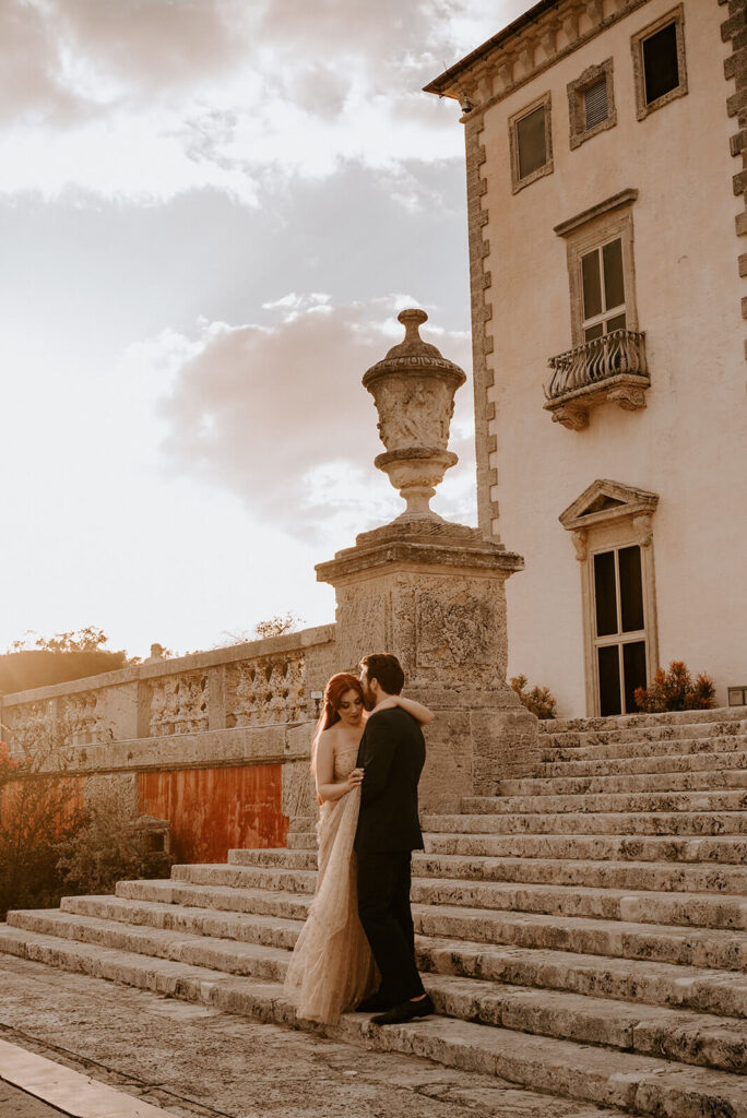 a couple hugs on the steps of Vizcaya Museum and Gardens in Coconut Grove