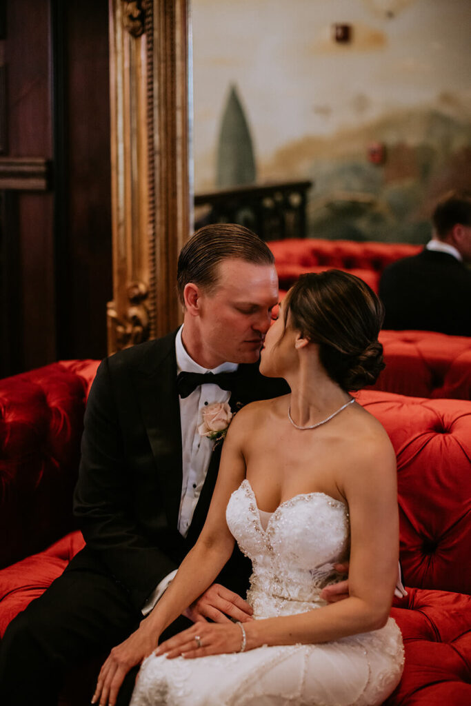 a couple poses on a couch at the Cruz Building on their wedding day