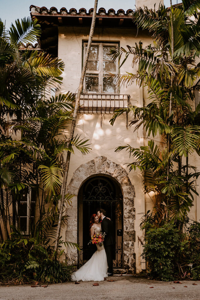 A couple poses on their wedding day in front of their wedding venue, Villa Woodbine in Coconut Grove