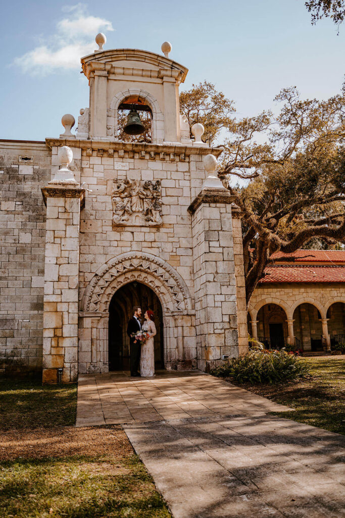 a couple poses in front of their miami wedding venue the Ancient Spanish Monastery 