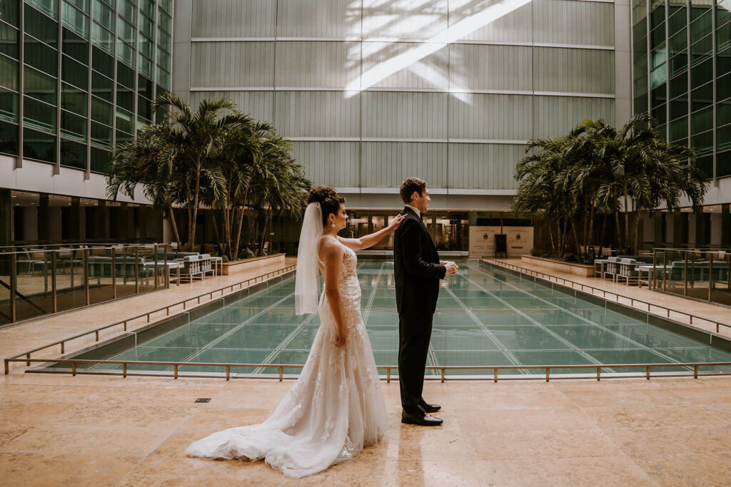 a bride touches his groom on the shoulder for their first look at their Brickell Miami wedding venue