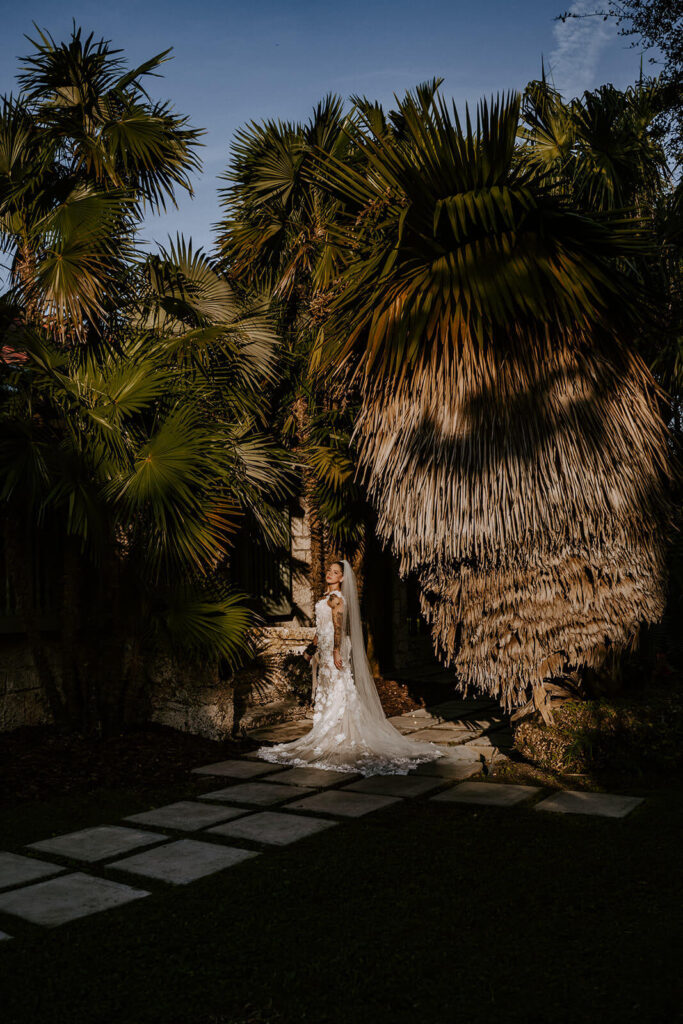 a bride poses in the direct sunlight with palms surrounding her in Miami florida