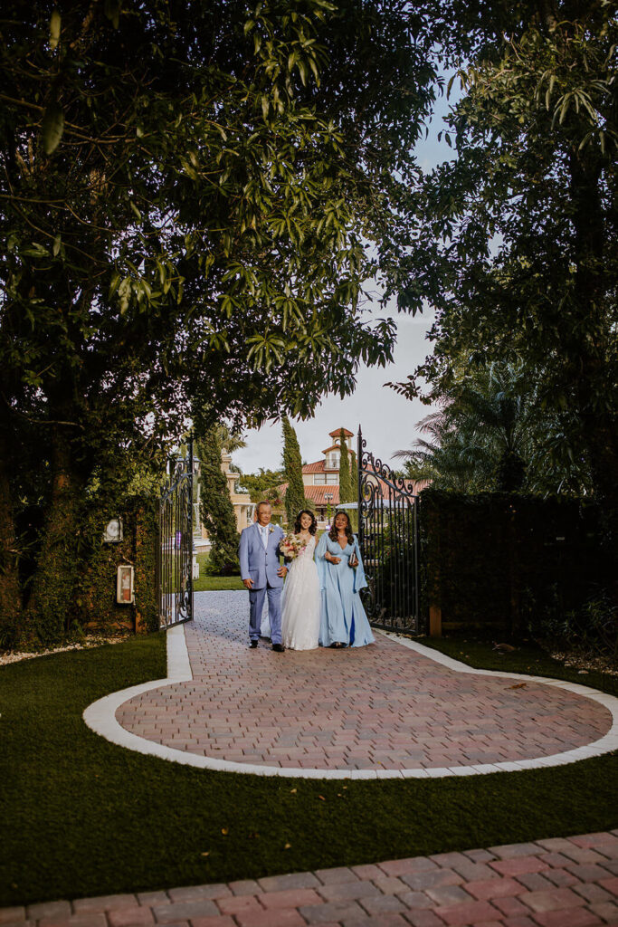 a bride walks down the aisle with both parents at her wedding