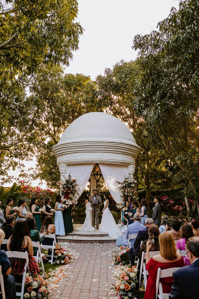 2 brides at their wedding ceremony surrounded by their family and friends at Villa Toscana in Miami