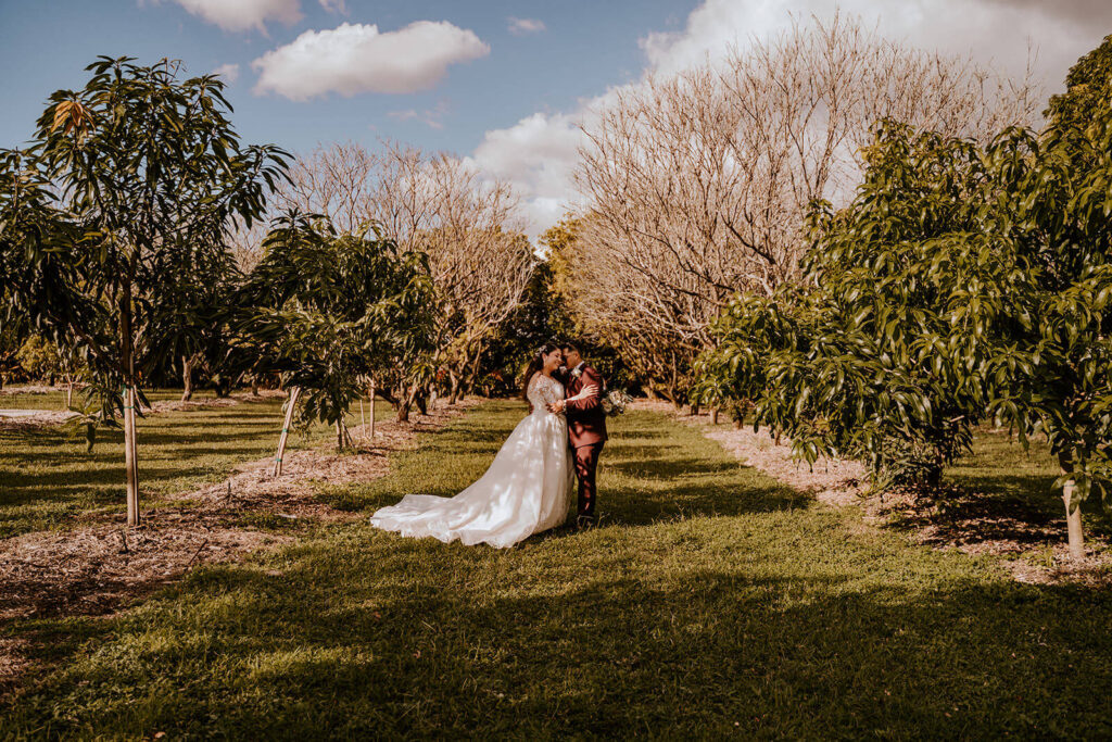 a couple poses in the middle of a field at their miami wedding venue